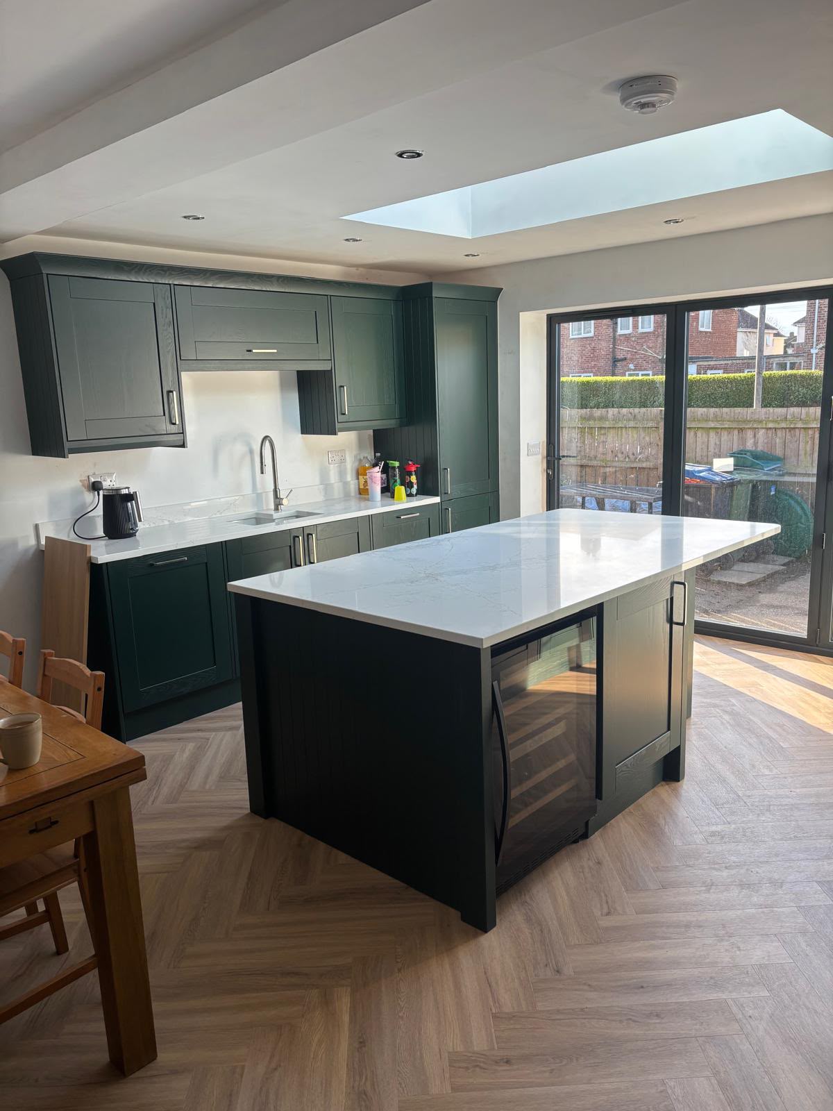 Fitted kitchen by Bridgeway Interiors: green shaker cabinets with quartz-waterfall island, Newcastle