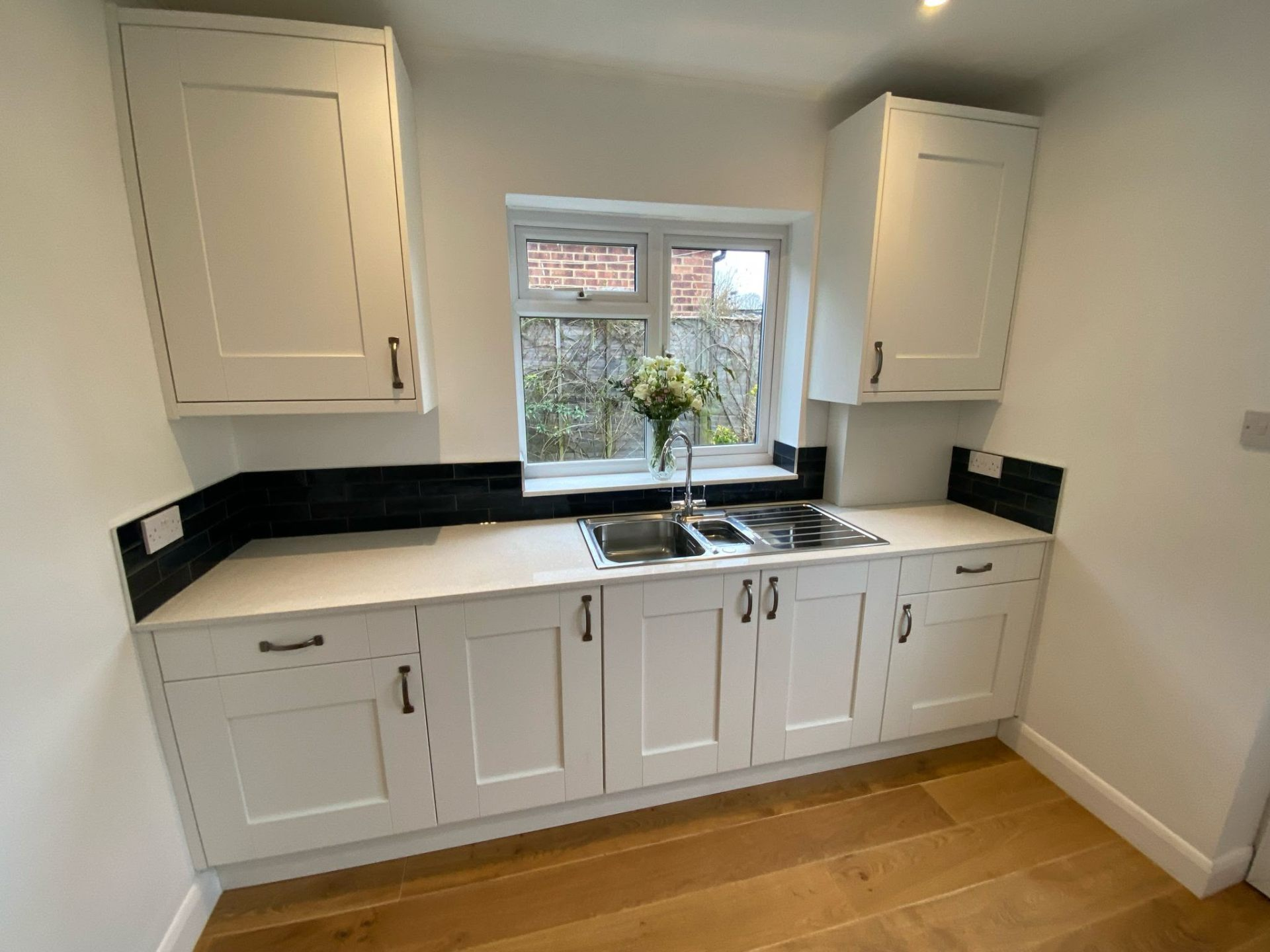 Fitted utility room by Bridgeway Interiors: cream shaker cabinetry with quartz worktop, black brick-tile splashback and stainless sink, Newcastle